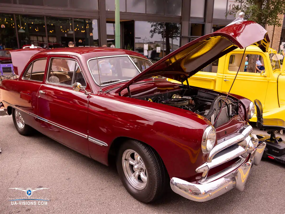 Step into the lively ambiance of a car show where a striking red car, labeled 