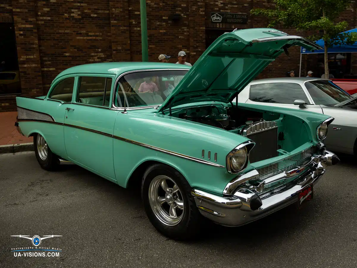 Step into a scene where a vintage green Chevrolet Bel Air takes center stage in a parking lot. This classic car, with its vibrant green hue, exudes timeless elegance and charm. A close-up of its wheel reveals intricate design details, emphasizing the craf
