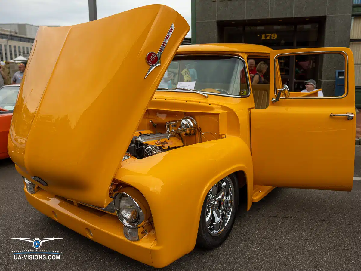 Classic yellow truck and sleek sports cars converge in a vibrant automotive setting.