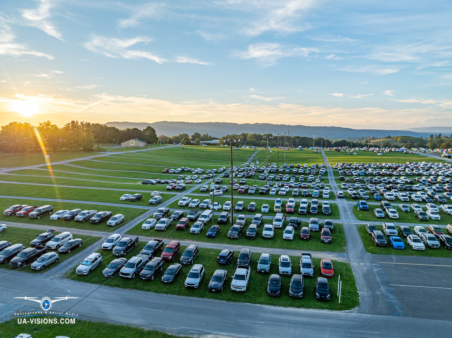 Sunset over a festival parking lot at Healing Appalachia, where cars rest before the night's encore.