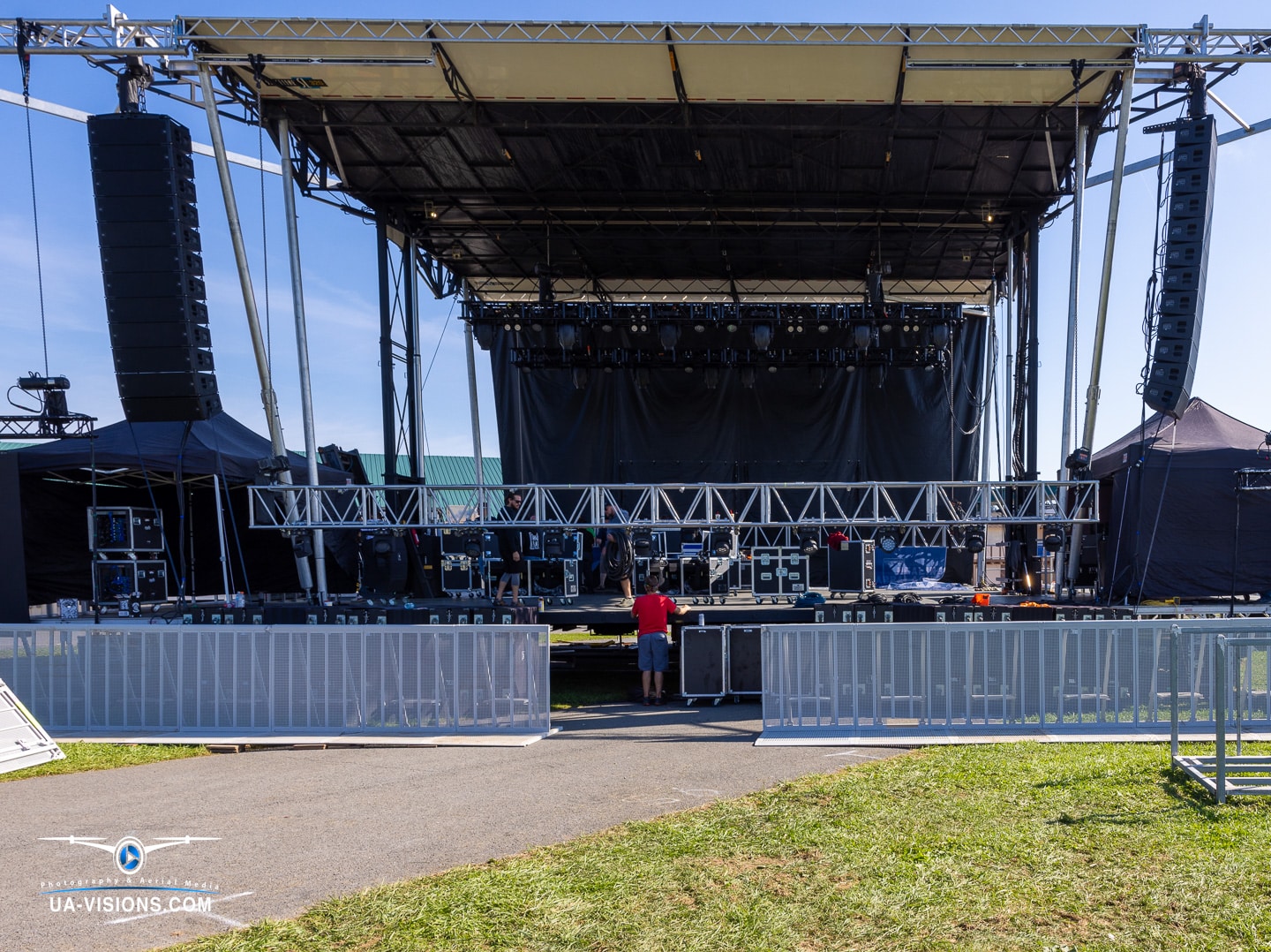 Close-up of outdoor concert stage with black drapes and professional audio equipment.