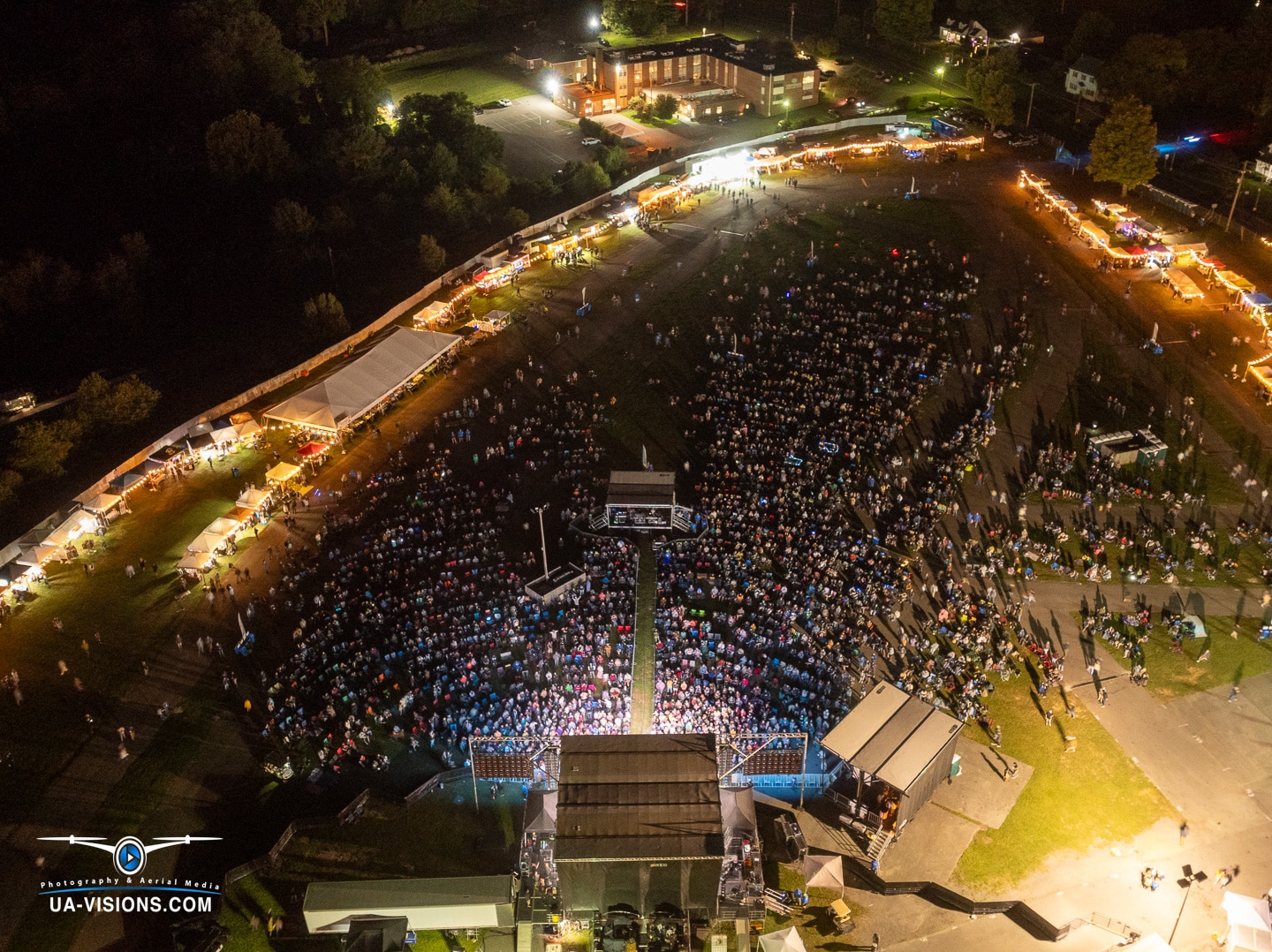 Aerial night view of a large outdoor Healing Appalachia event with crowds and festival lights.