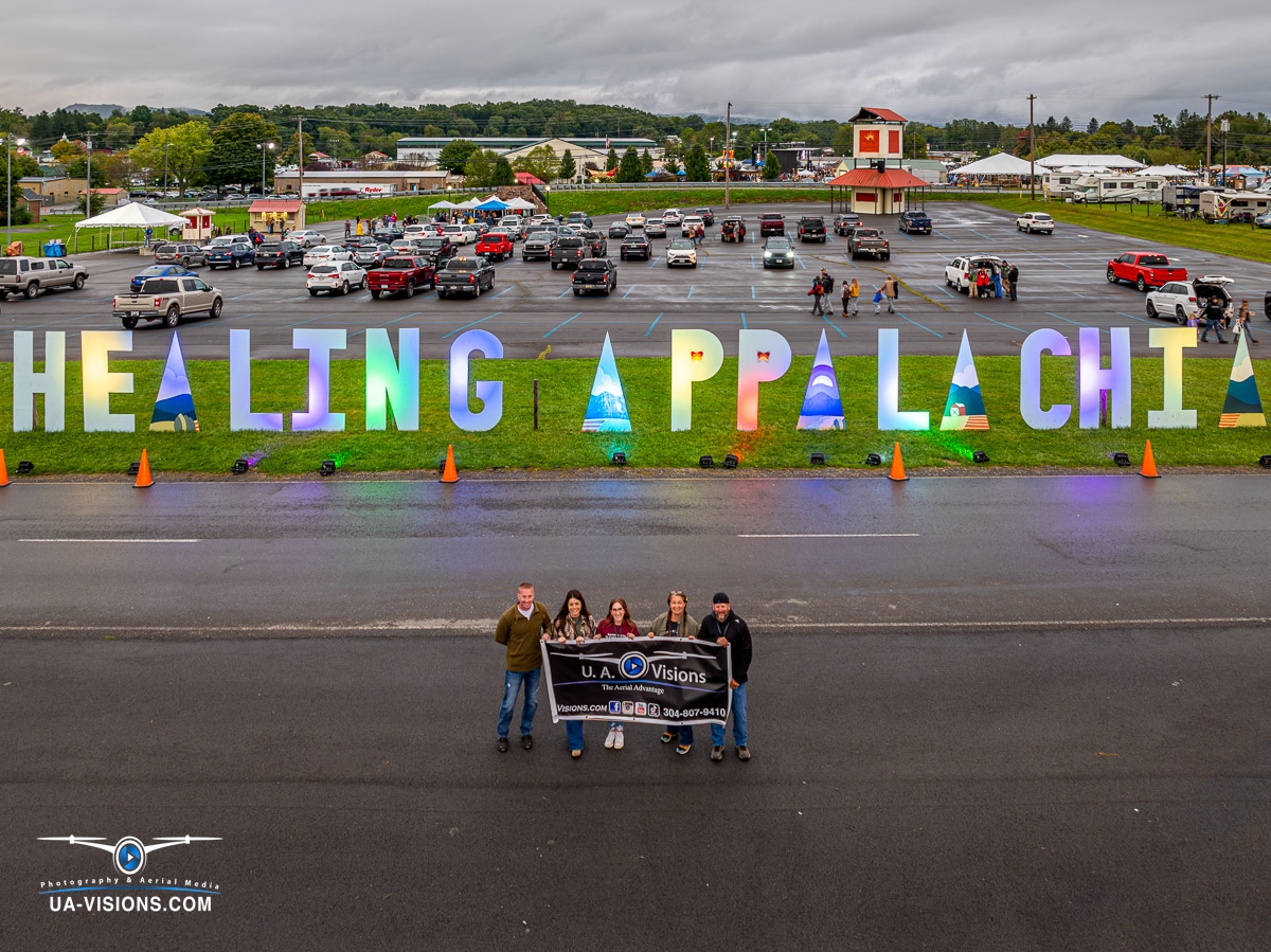 UA-Visions team standing proudly before the 'HEALING APPALACHIA' letter display at the event venue.
