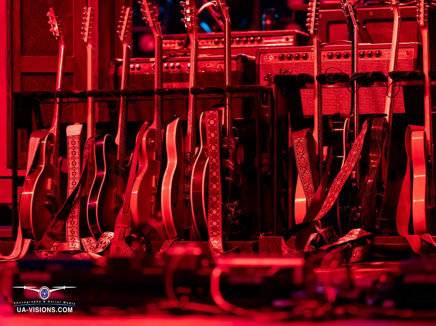 A lineup of guitars bathed in red stage light, silent before the Healing Appalachia concert crescendo.
