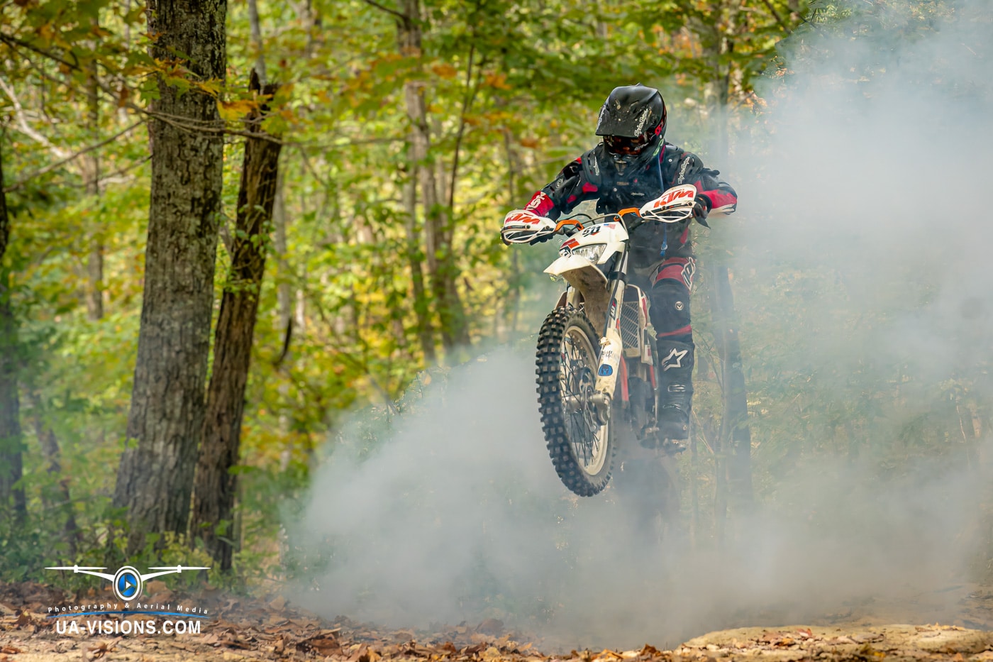 Motocross rider traversing a dusty trail amidst the dense forests of West Virginia.