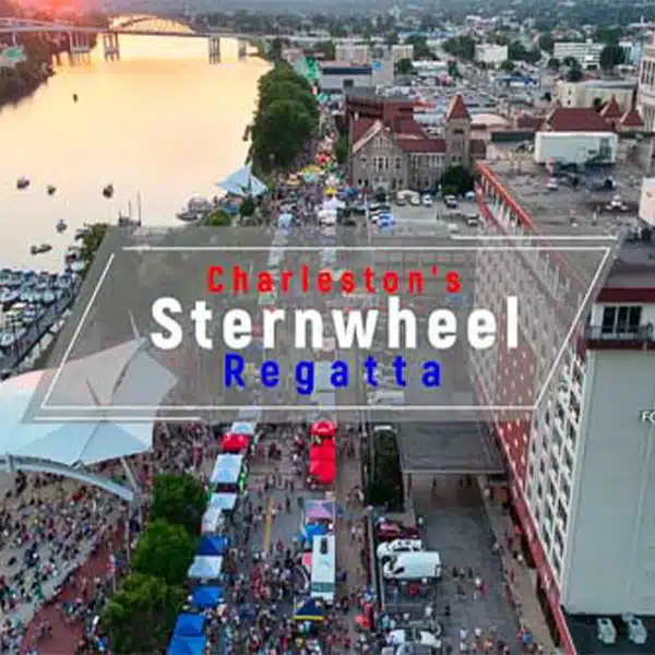 Drone photo of Charleston Sternwheel Regatta showcasing boats on the river, a bustling crowd, and cityscape at dusk.