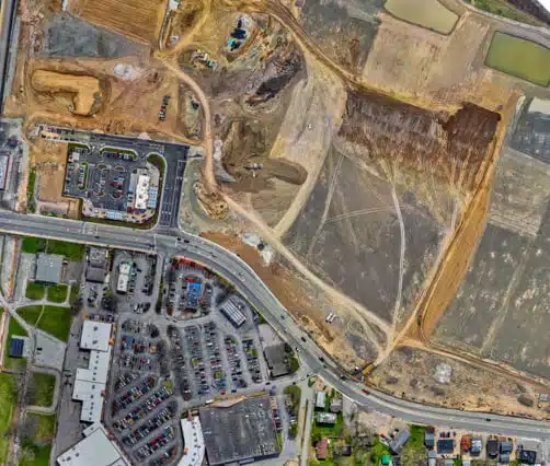 Aerial orthomosaic photo of a construction site with heavy machinery and an adjacent parking lot.