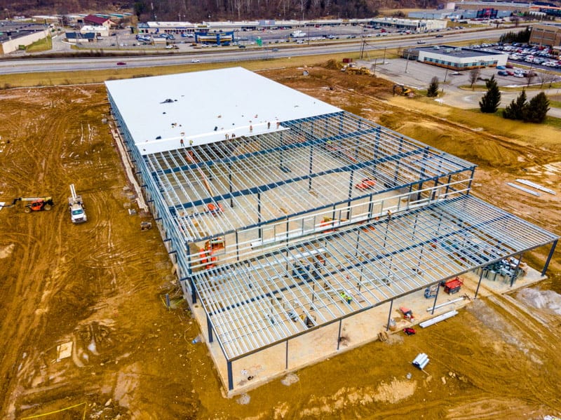 Aerial view of a steel building under construction, with a white truck and construction crew, captured by UA-Visions' drone.