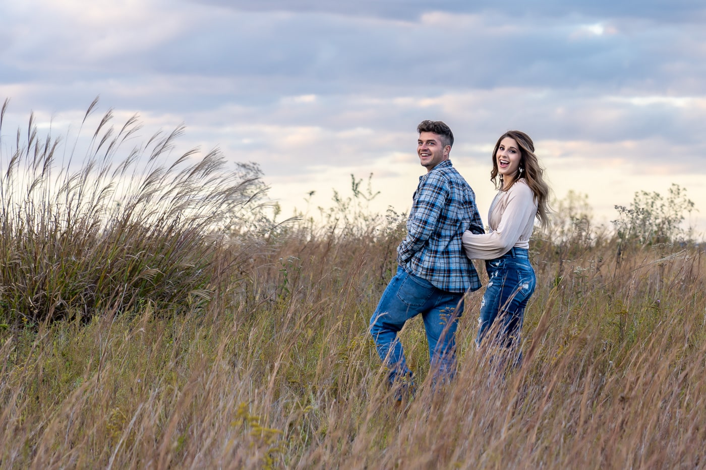 Back view of an engaged couple embracing in a field at sunset in Charleston, WV.