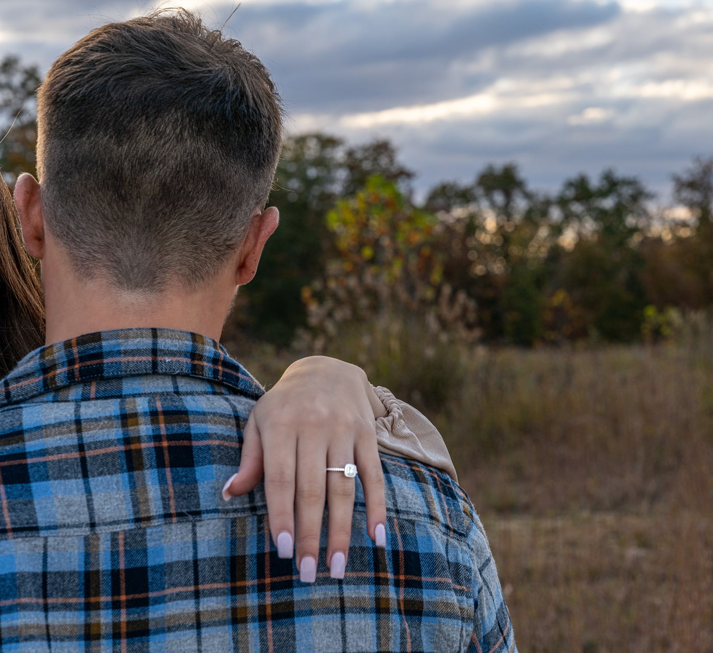 Engaged couple in a field with a scenic backdrop in Charleston, WV.