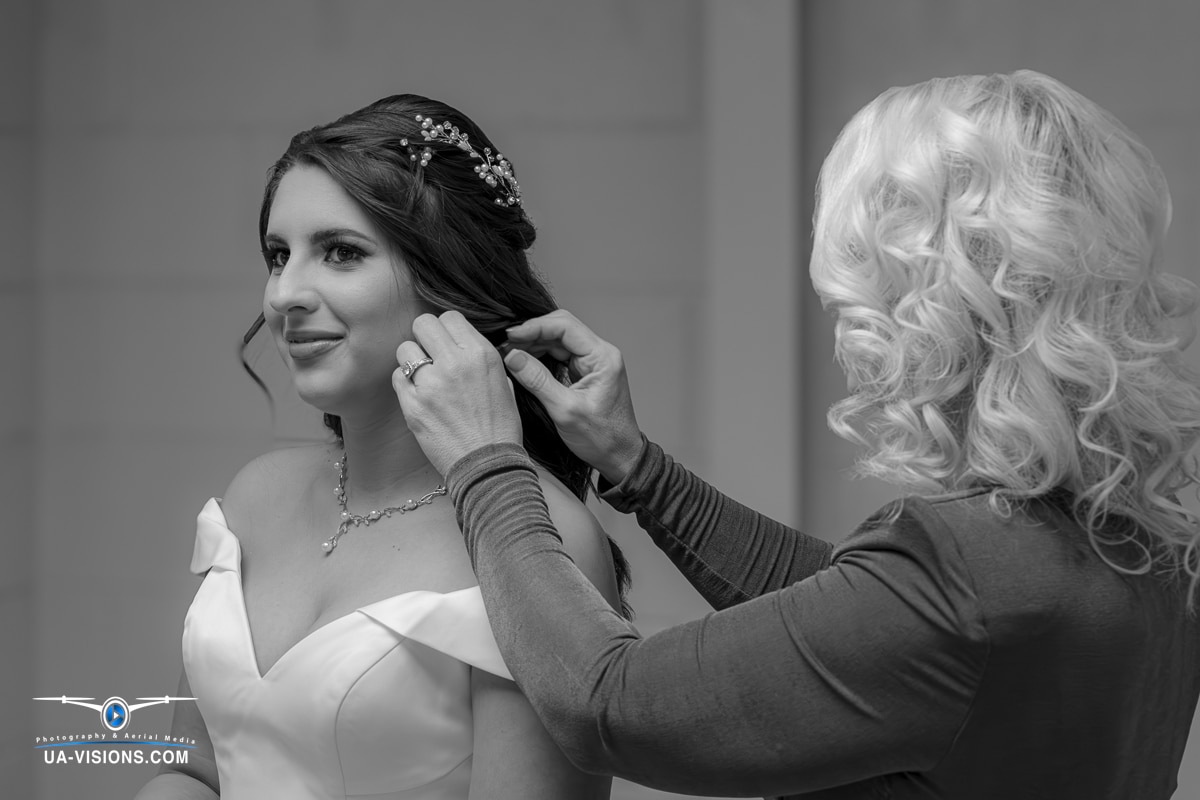 In a monochrome setting, a mother tenderly helps her daughter with her earrings on her wedding day in Hurricane, WV.