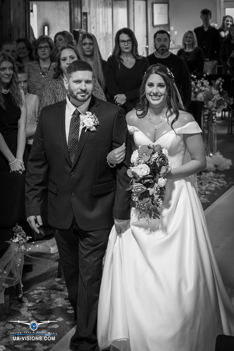 The father of the bride walks her down the aisle in a poignant black and white photo in Hurricane, WV.
