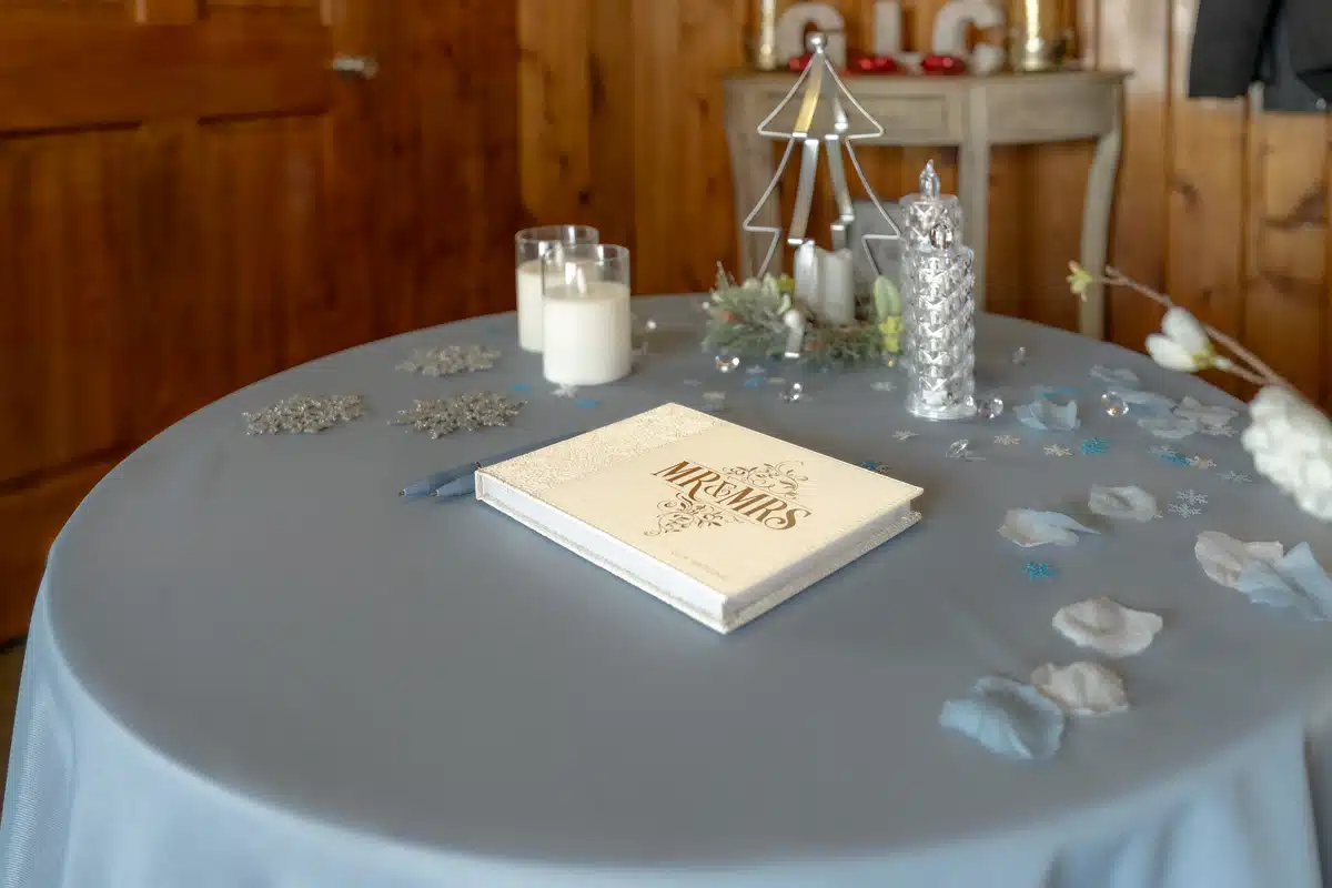 Reception guestbook table with 'Mr & Mrs' book, candles, and festive decorations.