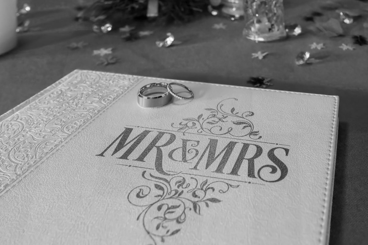 A close view of wedding rings on the 'Mr & Mrs' embossed guestbook at a reception.