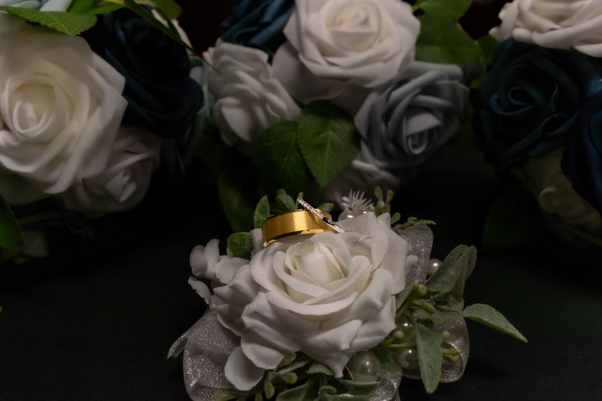 Wedding bands on a bridal bouquet with white and blue roses.