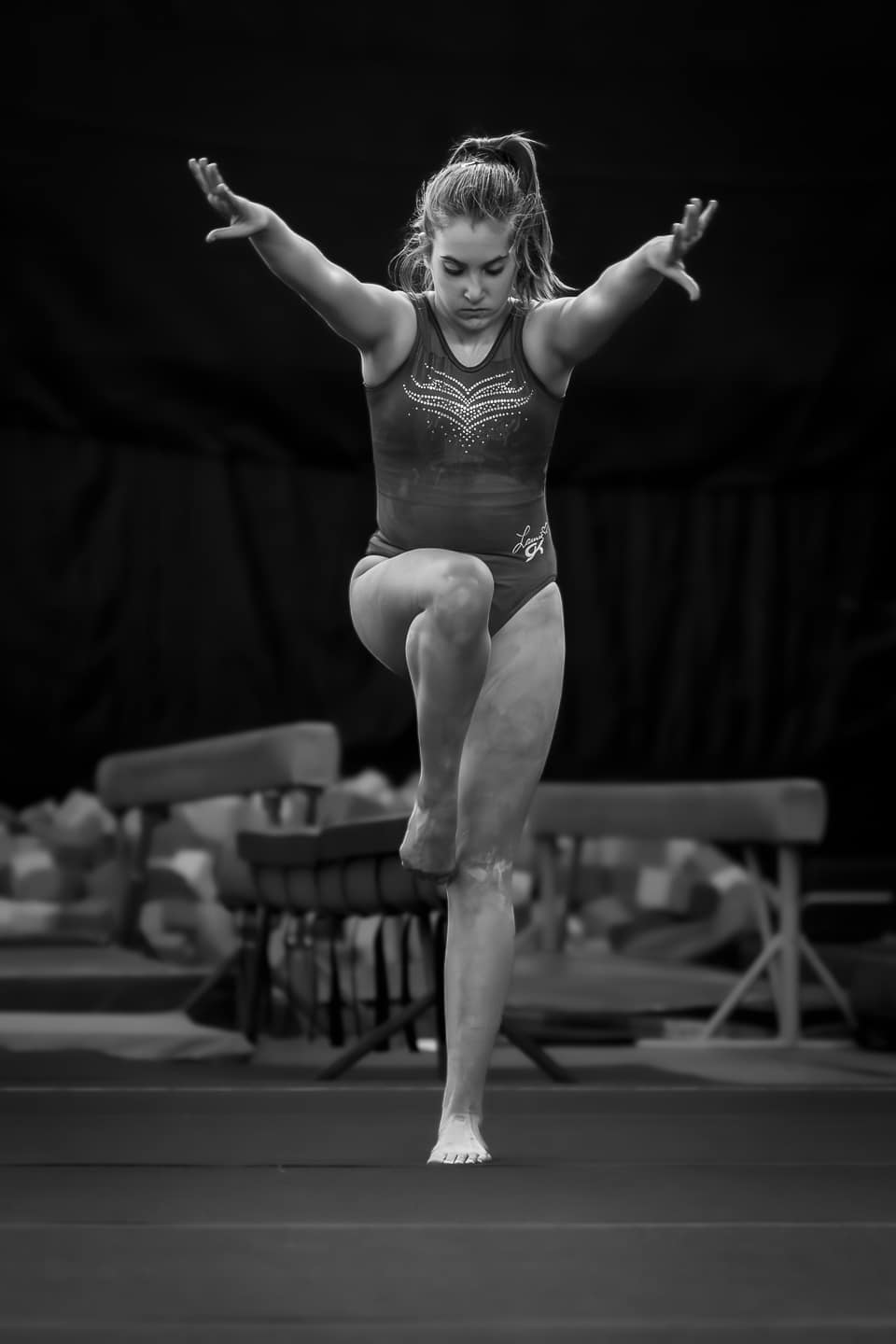 Female gymnast in mid-performance at a gymnastics competition, black and white image.